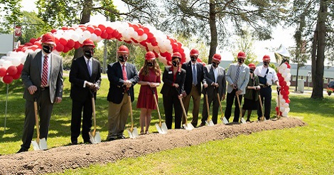 A group of 10 people stand with shovels at the groundbreaking for the Golisano Community Engagement Center.