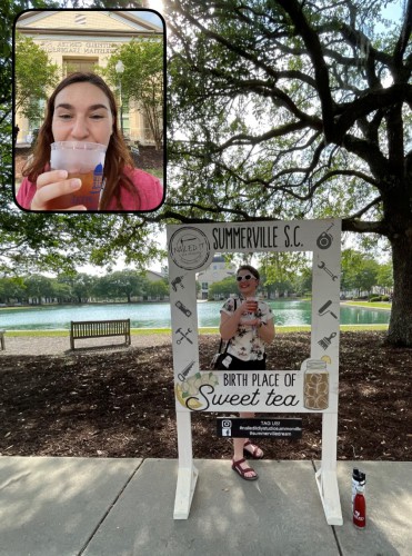 Addie sips a tea while Branwyn poses with a sign that says 