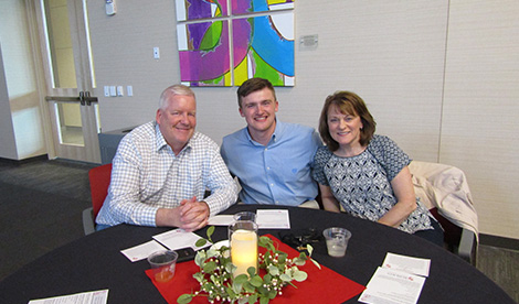 A business student smiles with his parents.