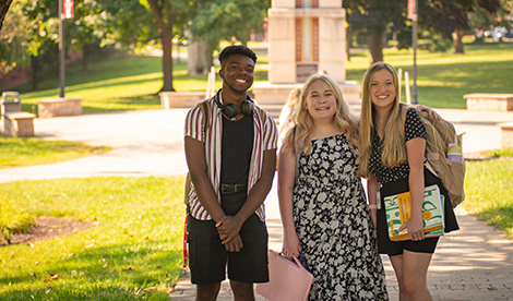 3 students smile on campus