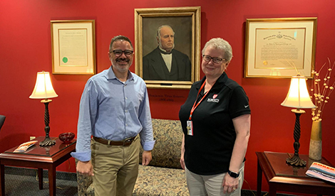 Kirk and Marna smile in front of a painting of BT Roberts