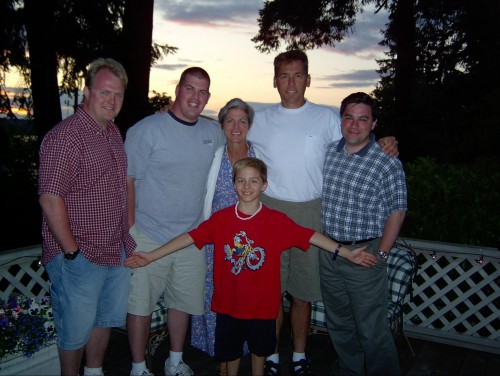 5 adults and 1 kid smile in front of the setting sun