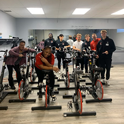 Students pose on and around exercise bikes