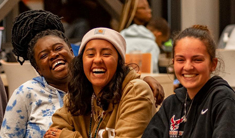 3 students smile and laugh together.