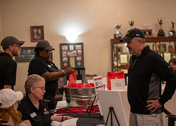 Marna sits at table as a golfer checks in for the tournament