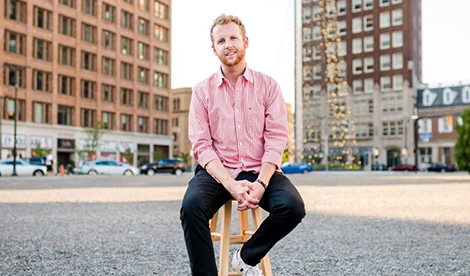 Stephen Carter smiles while sitting on a stool