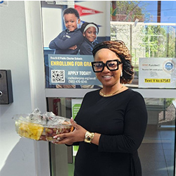 Teacher stands outside and smiles with a fruit tray.