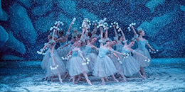 Young women perform ballet in matching blue dresses on a stage with a blue backdrop