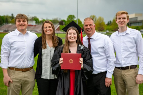 The Otto family smiles. The young woman in the center holds a diploma.