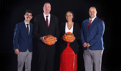 4 assistant coaches smile. 2 of them hold basketballs.