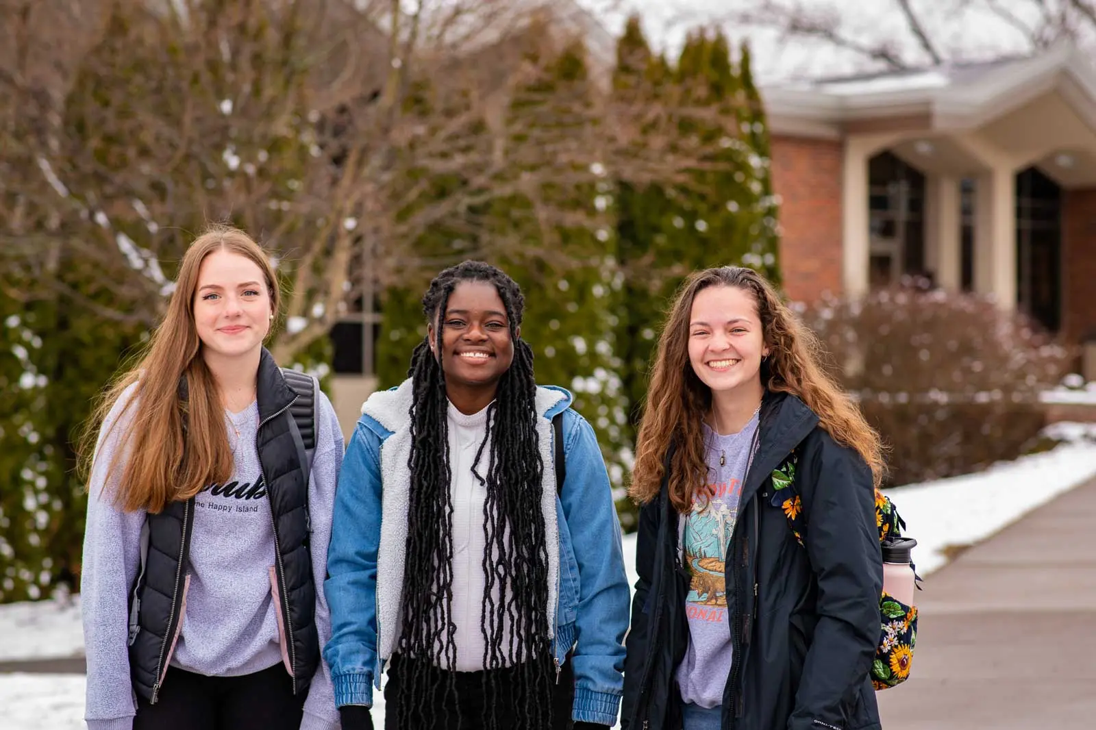 Three students smiling in the snow